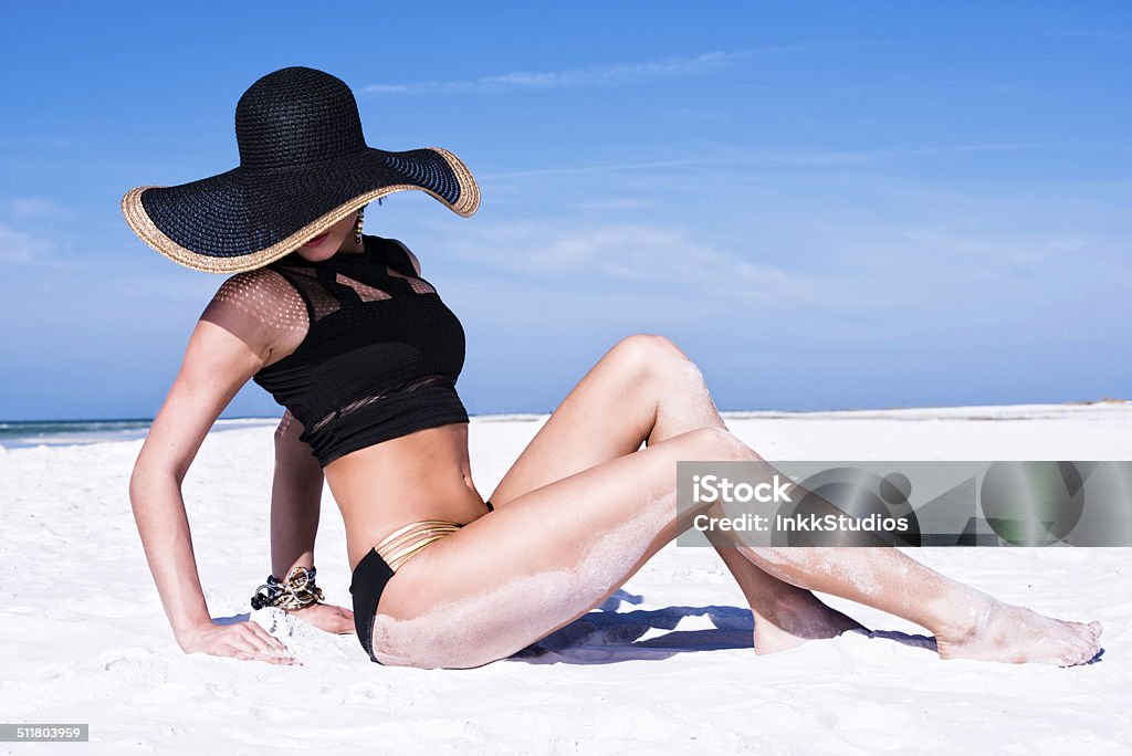 Elegant Tan Elegant Woman on a beach suntanning with Sunhat 20-29 Years Stock Photo