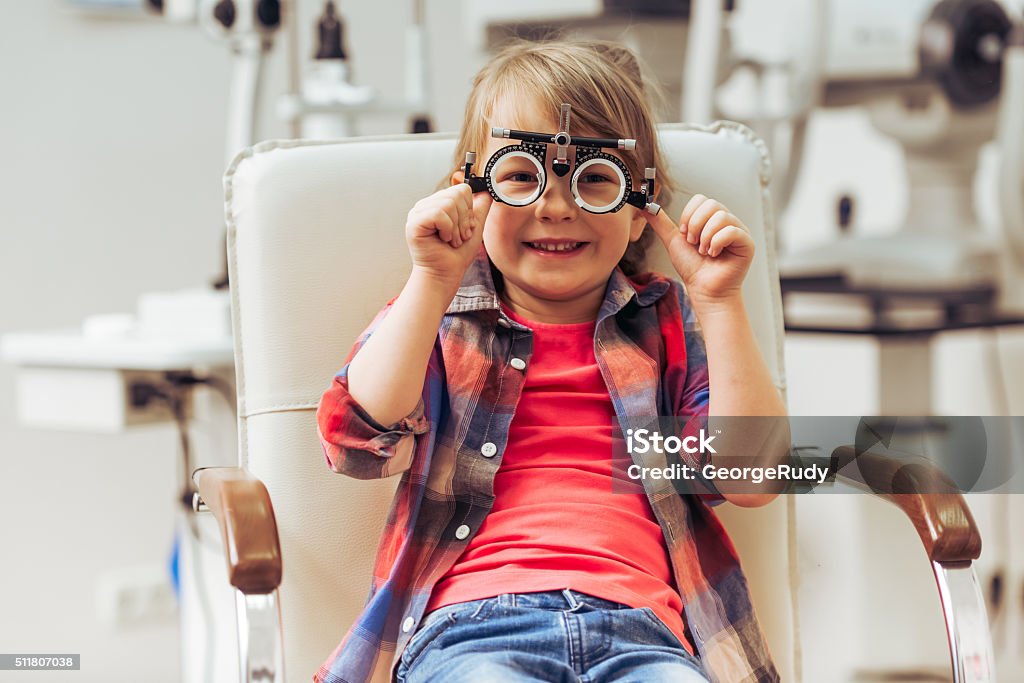 At the ophthalmologist Little boy looking at camera and smiling while sitting on chair at the ophthalmologist Optometrist Stock Photo
