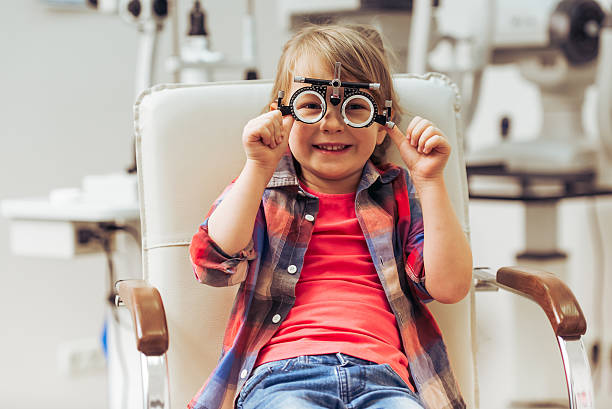 At the ophthalmologist Little boy looking at camera and smiling while sitting on chair at the ophthalmologist optometrist stock pictures, royalty-free photos & images