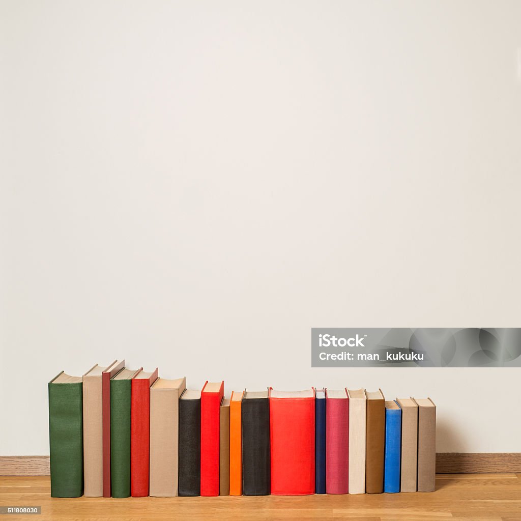 Old books on wooden floor Old colorful books on wooden floor near the white wall Bookshelf Stock Photo