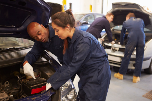 Teacher Helping Female Student Training To Be Car Mechanics