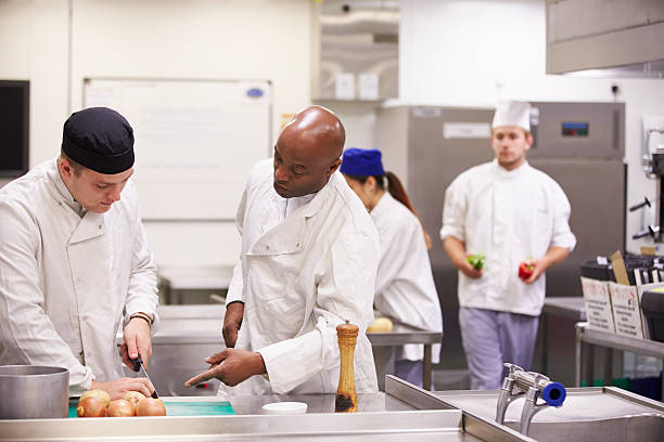 professor ajudar os alunos a trabalhar na formação de catering - chef trainee cooking teenager imagens e fotografias de stock