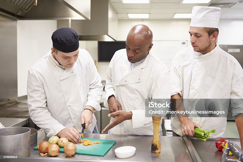 Insegnante aiutando gli studenti di formazione a lavoro In Catering - Foto stock royalty-free di Corso di formazione