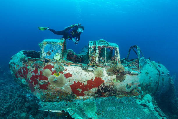 II WW Sunken Airplane Wreck -Palau This navy floatplane, an Aichi E13A1-1 or Jake type reconnaissance seaplane is one of the most intact wrecks in Micronesia, resting at 45 feet (15m). Beautiful scenario of a II WW Japanese seaplane sunken and a female scuba diver in Palau - Micronesia. The Jake could be found in many lagoons where the land mass did not support an airfield, but they also operated from cruisers and battleships. Two of the planes can be seen (in Palau) in very shallow waters in a cave of Babelthuap. palau stock pictures, royalty-free photos & images