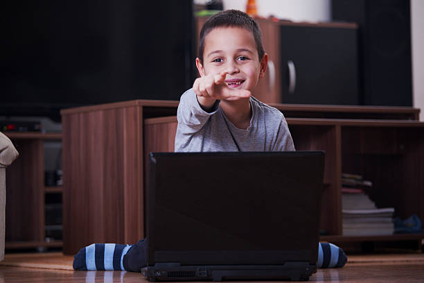istock Boy with laptop showing with a finger at camera 511812950