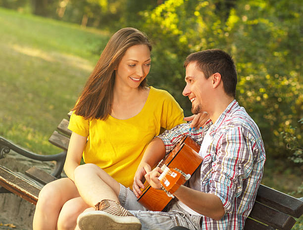 istock Young couple playing guitar at the park 511844747