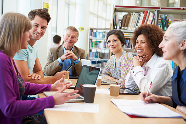 Group Of Mature Students Collaborating On Project In Library Group Of Mature Students Collaborating On Project In Library With Laptops Smiling middle age adult studying stock pictures, royalty-free photos & images