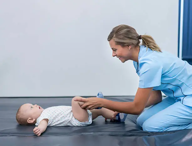 Happy baby in physical therapy with physiotherapist - early stimulations concepts