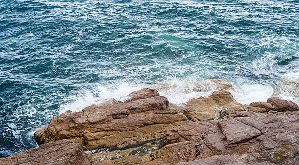 istock Splashing ocean waves crashing against bare rocks 511854144