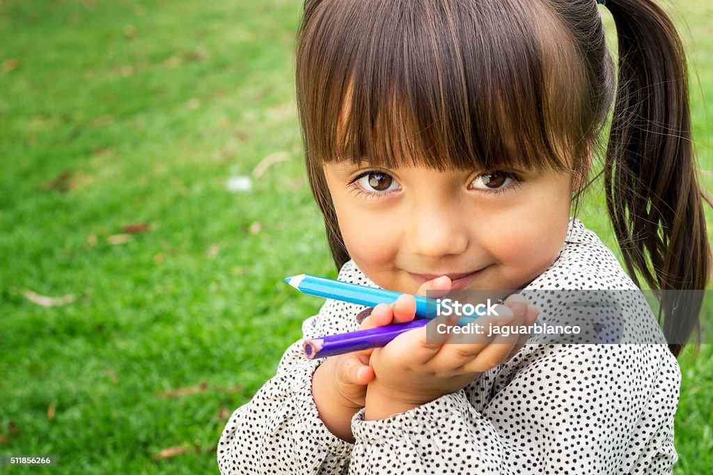 Little girl with color pencils Horizontal close up portrait of 4 year old girl holding color pencils looking at the camera and smiling. Child Stock Photo