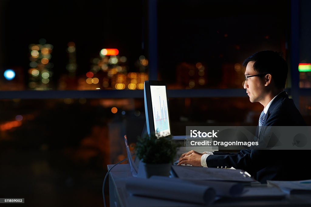 Working in darkness Financial manager working alone in dark office Working Late Stock Photo
