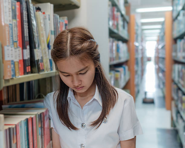 istock thai girl student in uniform reading a book in library 511859278