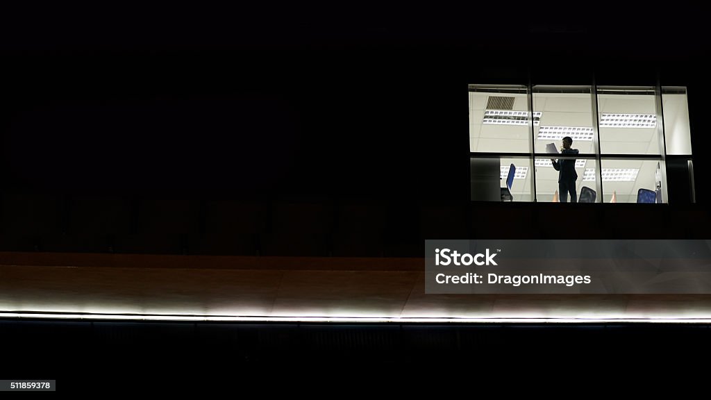 Office building at night Businessman working in office at night, view outside of the building Working Late Stock Photo