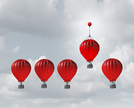 Competitive edge and business advantage concept as a group of hot air balloons racing to the top but an individualleader with a small balloon attached giving the winning competitor an extra boost to win the competition.