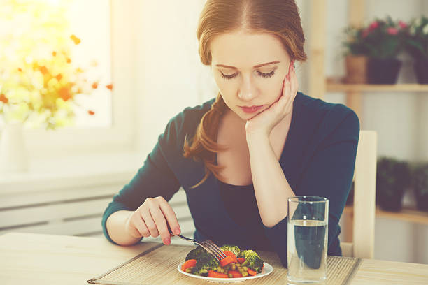 istock young sad woman eats vegetables at home in the kitchen 511863694