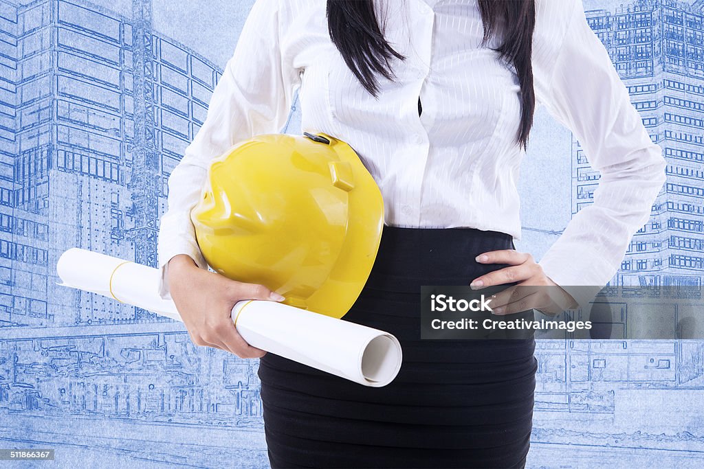 Close-up safety helmet on blueprint Close-up of businesswoman with safety helmet on blueprint background Helmet Stock Photo