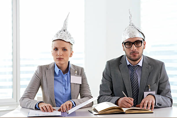 Tin foiled business couple Businessman and businesswoman in tin foil hat sitting at office table tin foil hat stock pictures, royalty-free photos & images