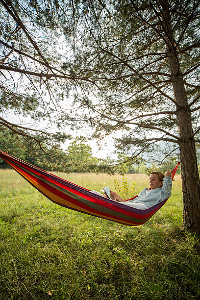 istock Woman on hammock at sunset using digital tablet digital tablet 511869167