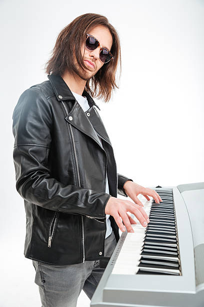 istock Confident young keyboardist in sunglasses standing and playing on synthesizer 511870972