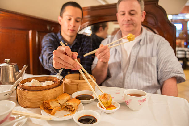 A traditional Chinese set of restaurant cutleries comprising of a typical white bowl, saucer, a pair of chopsticks, teacup and a small saucer of chili sauce.