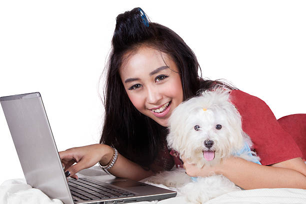 istock Cheerful model with dog and laptop on bed 511876504