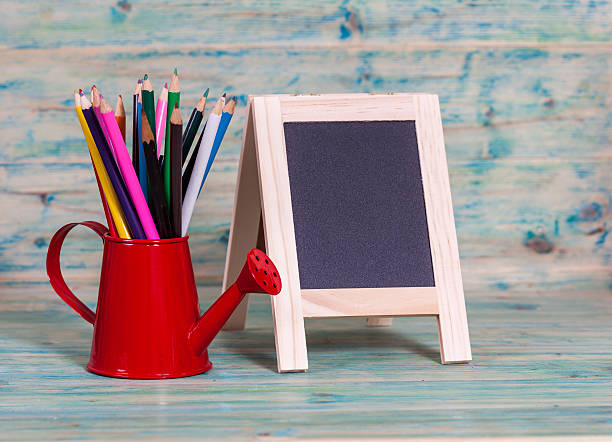 istock color pencil in red watering can and small blackboard 511880802