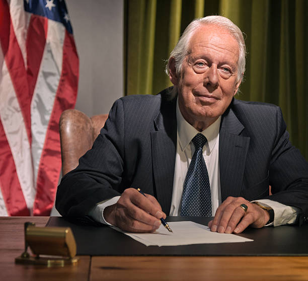 istock Big boss president writing behind desk with american flag. 511884523
