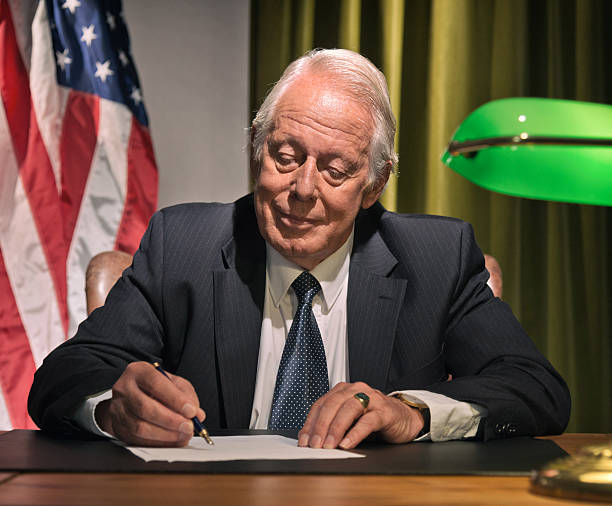 istock Big boss president writing behind desk with american flag. 511884565
