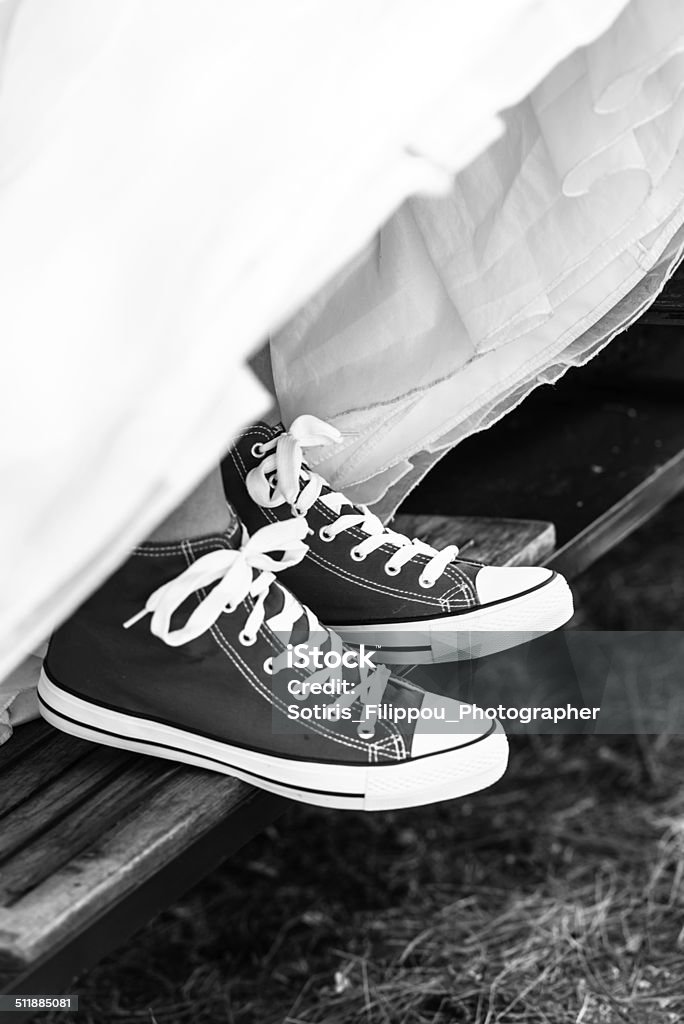 The bride wearing sport shoes. Black and white photo of the bride wearing sport shoes. Canvas Shoe Stock Photo