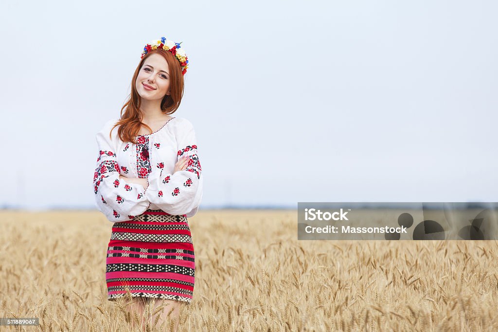 Redhead girl in national ukrainian clothes on the wheat field. Ukraine Stock Photo