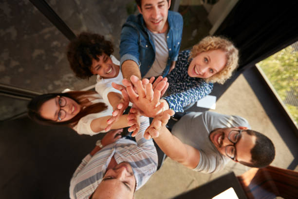 réussite de l'équipe de professionnels haute fiving - holding hands human hand holding multi ethnic group photos et images de collection