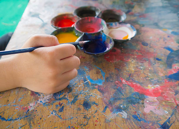 istock Kid's hand holding paintbrush with the palette 511923366