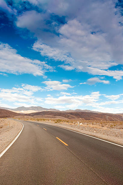 tradizionale americano autostrada tra alte montagne di morte valle - arid climate asphalt barren blue foto e immagini stock