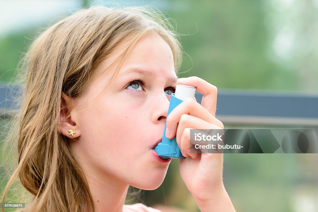 Pretty girl using asthma inhaler Girl having asthma using the asthma inhaler for being healthy - shallow depth of field - asthma allergy concept Child Stock Photo