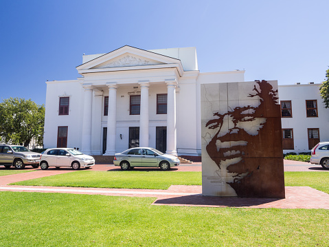 Stellenbosh, South Africa - February 16, 2016: Bronze coated statue of Nelson Mandela in front of Stellenbosch Town Hall on a sunny day.