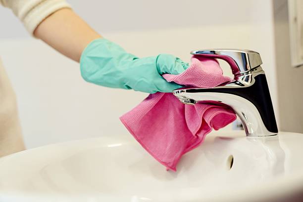 istock Female hands with green rubber protective gloves cleaning tap 511937578