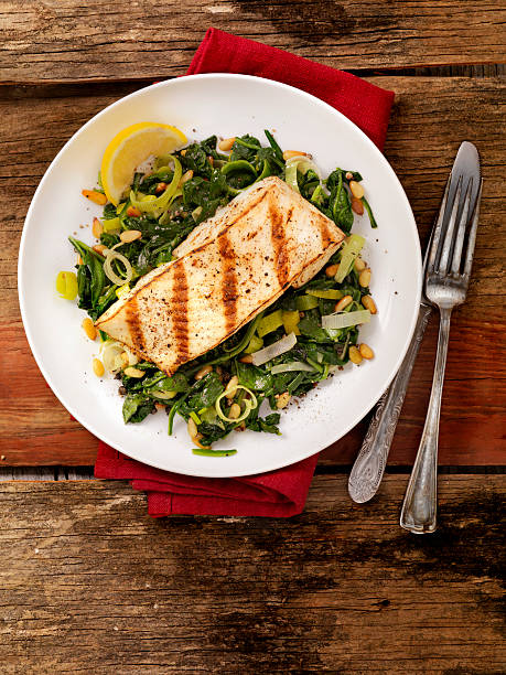 pesce grigliato con spinaci, porri, pinoli - healthy eating close up lemon nut foto e immagini stock