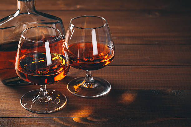 Two glasses of cognac and bottle on the wooden table. stock photo