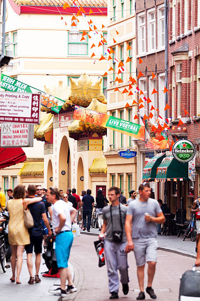 Chinatown and Fo Guang Shan temple Amsterdam, The Netherlands - June 9, 2014: View along street in Chinatown of Wallen in Amsterdam in summer: in background is chinese temple and monastery Fo Guang Shan. People and tourists are walking along street. Between buildings are orange pennants and banner for FIfa worldcup 2014. wellen stock pictures, royalty-free photos & images