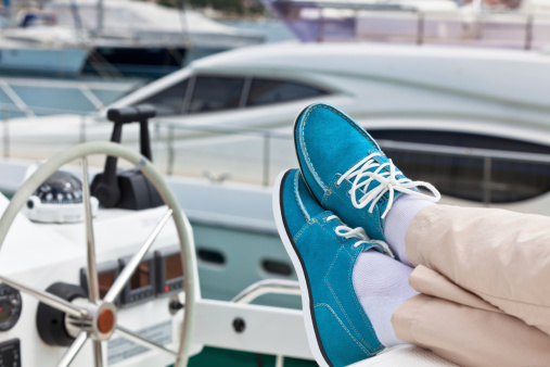 A pair of human legs in pants and bright blue topsiders on yacht background. Yachting