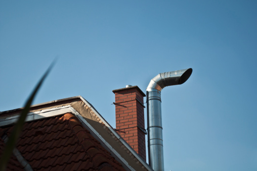 Exhaust pipe and chimney in front of a clear blue sky