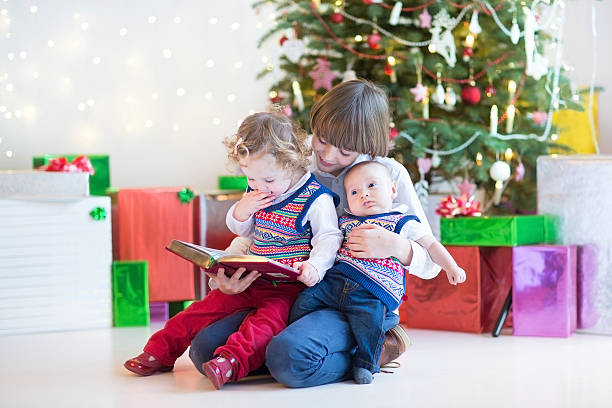 istock Portrait of three kids reading book under Christmas tree 511976039