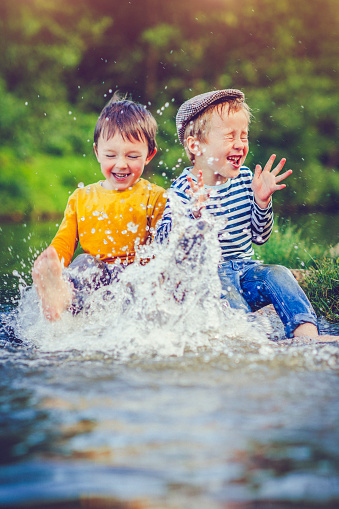 Little boys playing in a lake in spring