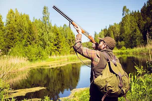 istock Hunter Pointing a Gun to the Sky in a Swamp 511978962