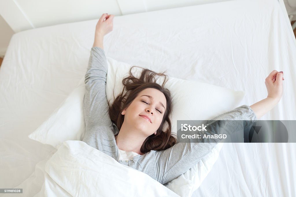 Rise and shine Young beautiful, woman waking up fully rested. Mattress Stock Photo