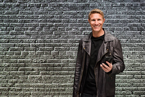 istock Smiling casual man in front of brick wall 511982216