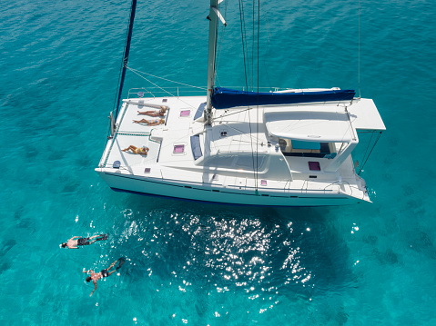 Aerial view of people snorkeling and relaxing on a beatiful catamaran anchored in clear tropical water in the Caribbean