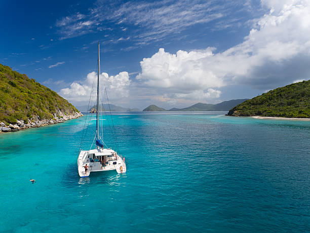Catamaran anchored by Lovango Cay, US Virgin Islands Aerial view of people relaxing on catamaran at anchor outside of Lavango Cay, United States Virgin Islands cay stock pictures, royalty-free photos & images