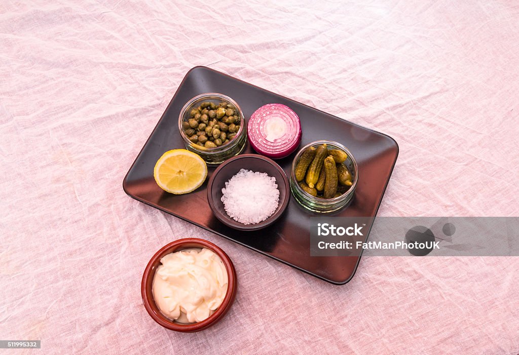 Tartare sauce separate ingredients, mayonnaise, salt, gherkins, Tray with individual ingredients to make tartare sauce, mayonnaise, salt, gherkins, capers, onion and lemon Above Stock Photo