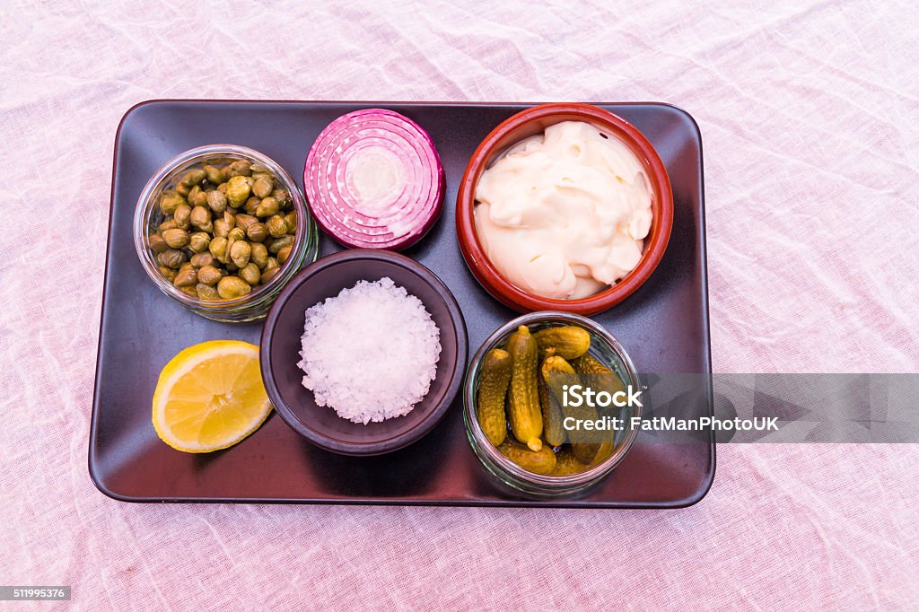 Tartare sauce separate ingredients, mayonnaise, salt, gherkins, Tray with individual ingredients to make tartare sauce, mayonnaise, salt, gherkins, capers, onion and lemon Above Stock Photo